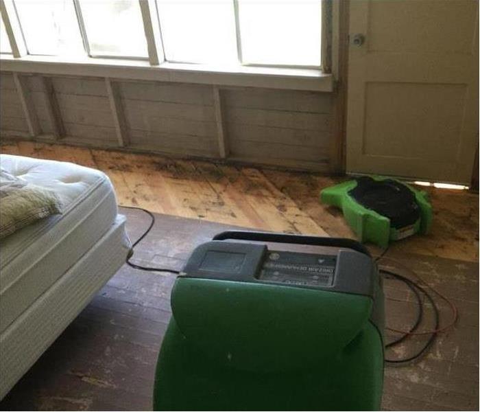 Air movers placed on wet area after storm damage in a room